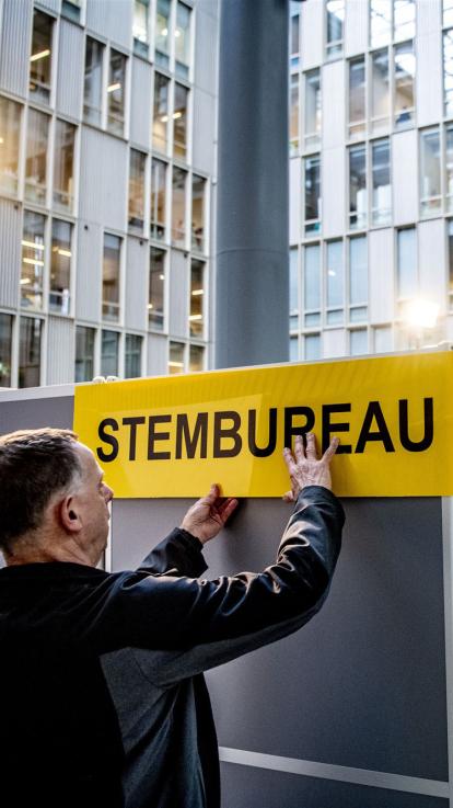 iemand hangt een bordje voor een stembureau op