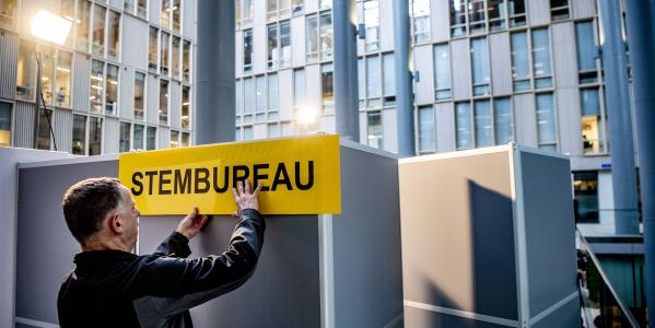 iemand hangt een bordje voor een stembureau op