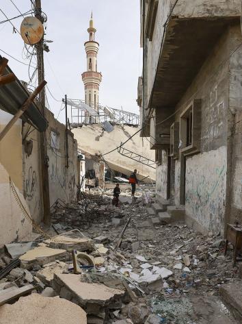 Man en jongen lopen door het puin van een moskee in Rafah