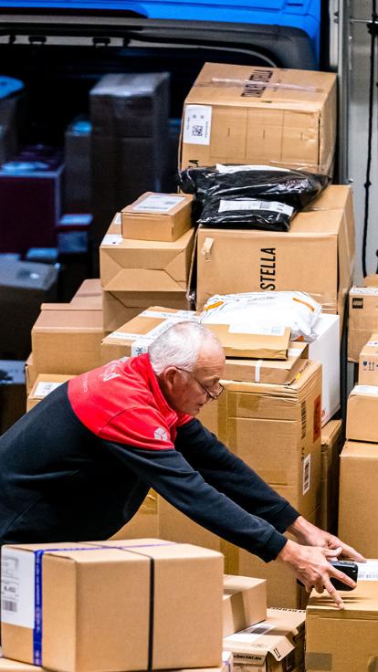 Postbezorger laadt pakketjes in in een bestelbusje