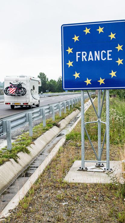 Een Nederlandse auto met caravan rijdt de Franse grens over 