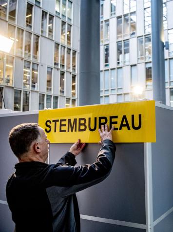 iemand hangt een bordje op met de tekst 'stembureau'