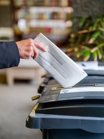 een stembiljet gaat in een stemcontainer