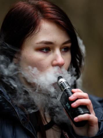 Een vrouw blaast rook uit van haar e-sigaret