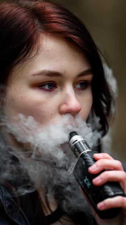 Een vrouw blaast rook uit van haar e-sigaret