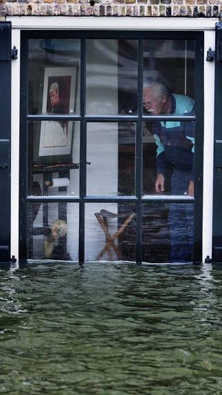 Man kijkt vanuit zijn raam naar water dat tot het raam komt.