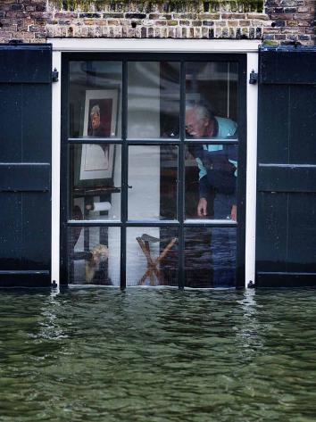 Man kijkt vanuit zijn raam naar water dat tot het raam komt.
