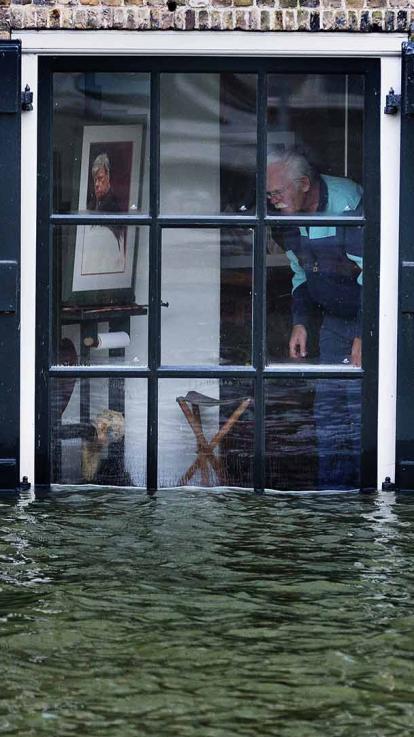 Man kijkt vanuit zijn raam naar water dat tot het raam komt.