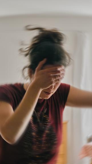 vrouw met hand op haar voorhoofd met 'draaiende' effecten eromheen