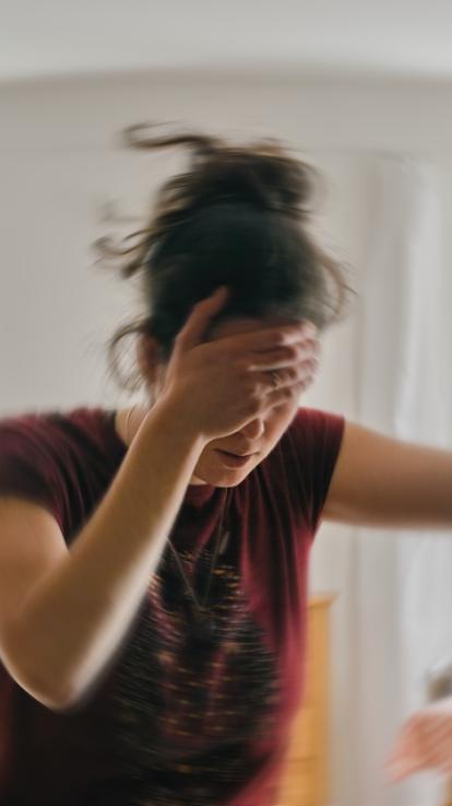 vrouw met hand op haar voorhoofd met 'draaiende' effecten eromheen