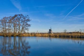 blauwe lucht boven het water en een molen