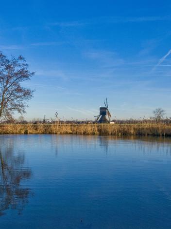 blauwe lucht boven het water en een molen
