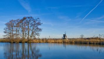 blauwe lucht boven het water en een molen