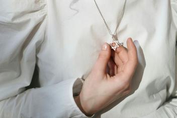 een vrouw houdt haar ketting met davidster vast