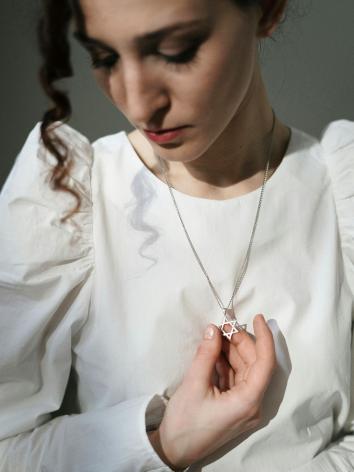 een vrouw houdt haar ketting met davidster vast