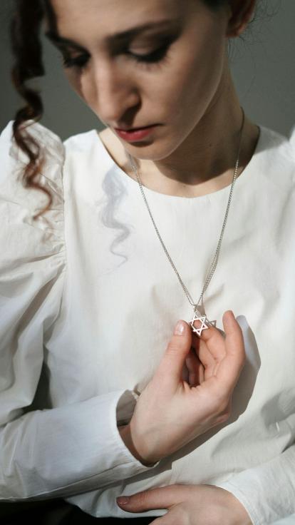 een vrouw houdt haar ketting met davidster vast