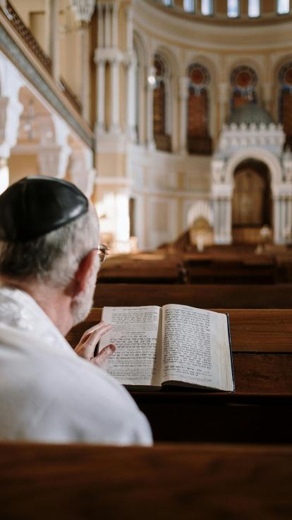 een man met een keppeltje leest een heilig boek in de synagoge
