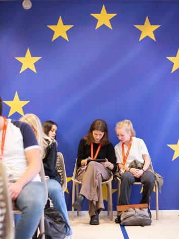 een foto van leerlingen bij ProDemos met als achtergrond de Europese vlag