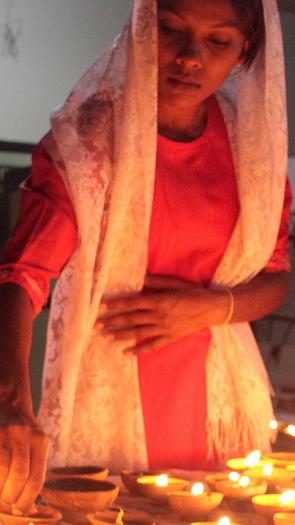 Twee vrouwen steken kaarsjes aan met Divali 