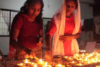 Twee vrouwen steken kaarsjes aan met Divali 