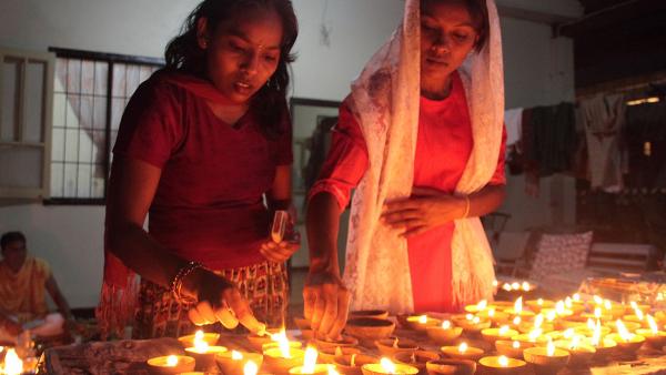 Twee vrouwen steken kaarsjes aan met Divali
