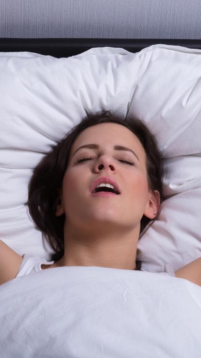 het gezicht van een vrouw die een orgasme heeft in bed
