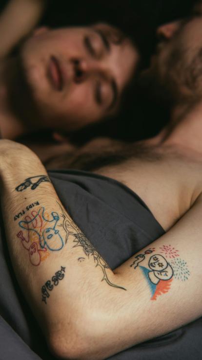 twee mannen liggen ontspannen knuffelend in bed samen