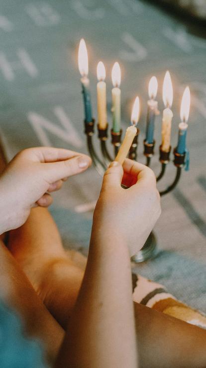 iemand steekt een kaarsje van een menora aan