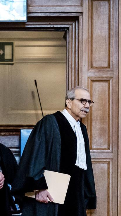 een rechter loopt met papieren in zijn hand 