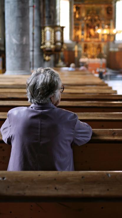 Een vrouw zit alleen bij een kerkdienst