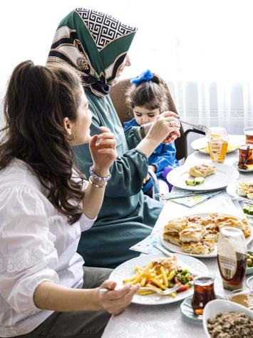 Een gezin zit samen aan een tafel vol met eten.