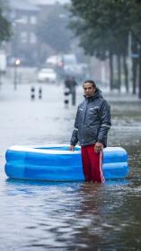 Een overstroomde straat met daarin een man en een opblaasbadje.