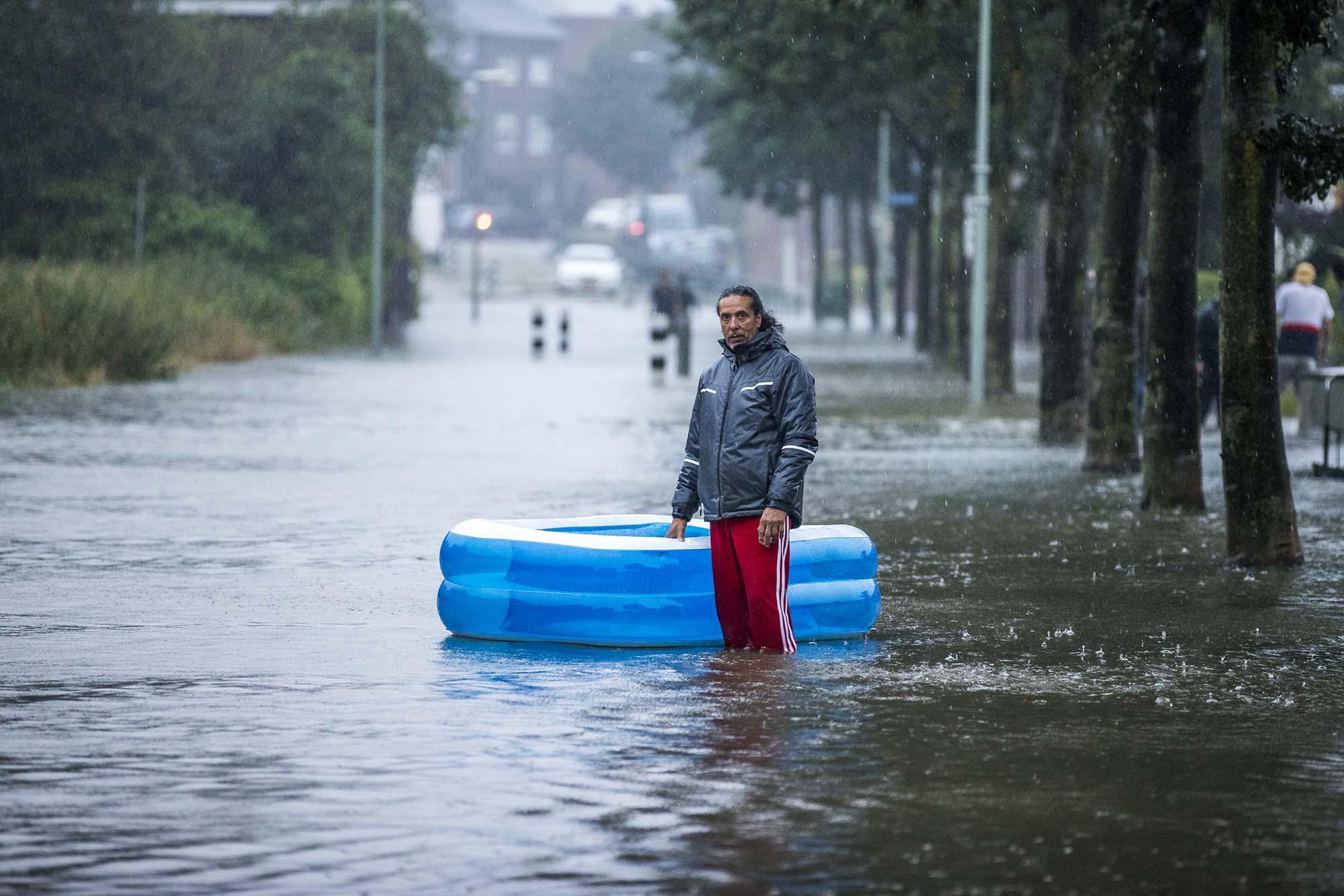 Een overstroomde straat met daarin een man en een opblaasbadje.