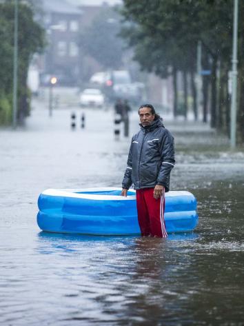Een overstroomde straat met daarin een man en een opblaasbadje.