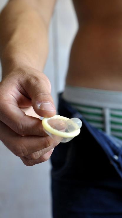 Jongen met open broek houdt condoom vast