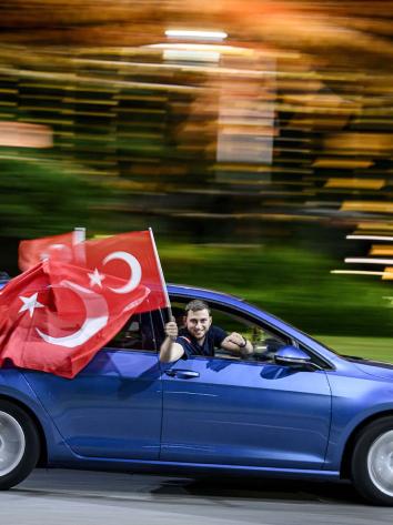 Man houdt Turkse vlag uit de auto terwijl de auto rijdt.