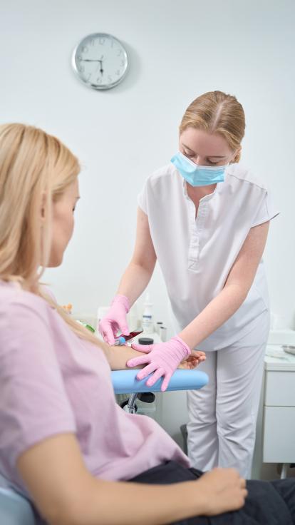 Een verpleegkundige prikt bloed bij een vrouw