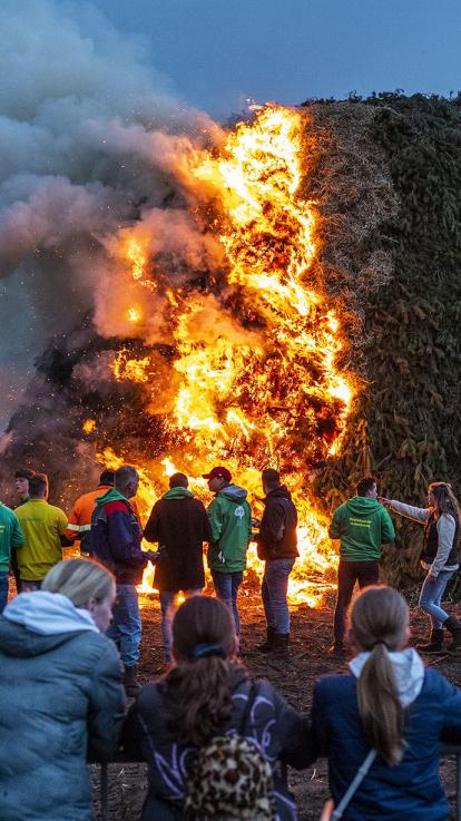 groep mensen staat rondom een groot paasvuur