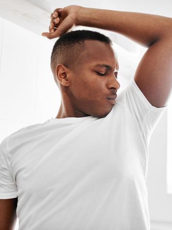 Man ruikt aan zijn oksel en trekt een vies gezicht