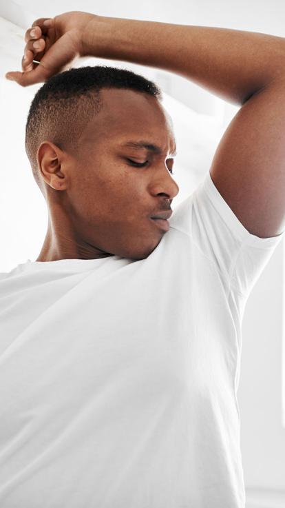 Man ruikt aan zijn oksel en trekt een vies gezicht