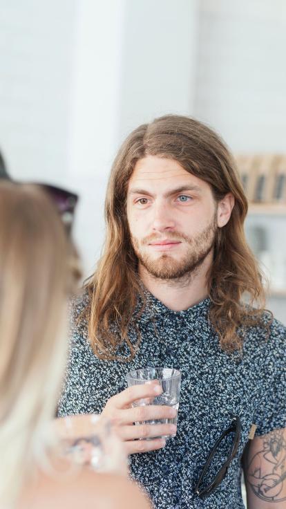 iemand luistert met een glas in z'n hand naar iemand anders