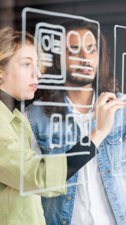 twee mensen tekenen tabellen op een doorzichtig bord