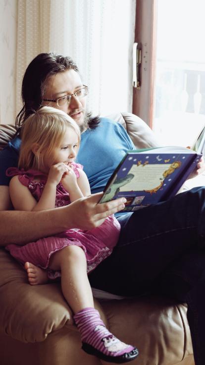 een vader leest zijn dochter voor