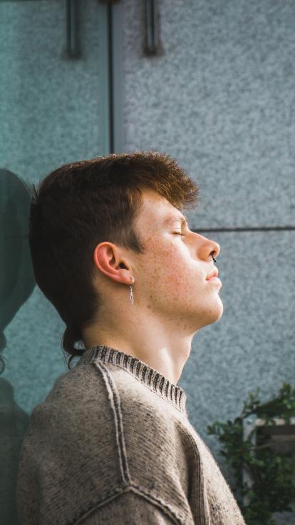 een jongen met zijn ogen dicht en hoofd tegen de muur
