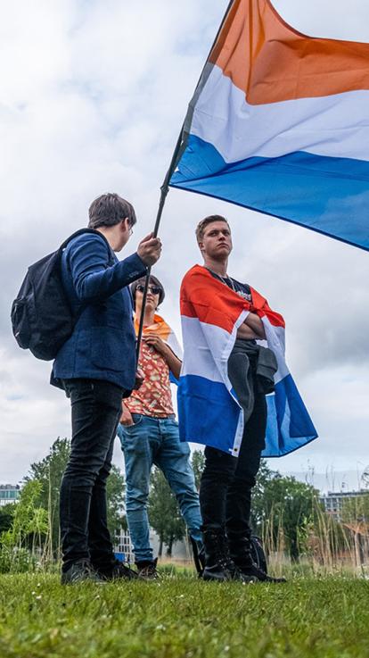 Personen die met een Nederlandse vlag staan 