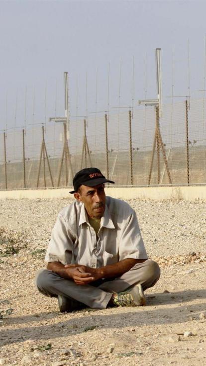 Een Palestijnse boer wacht tot hij door de poort van de muur heen mag