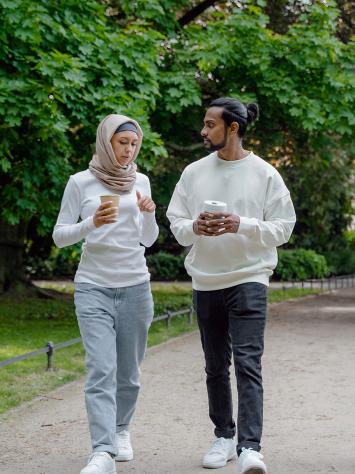 Een vrouw met hoofddoek loopt met een man door het park