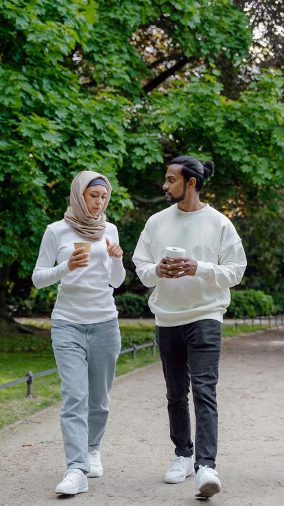 Een vrouw met hoofddoek loopt met een man door het park