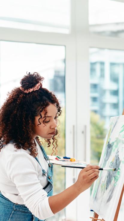 Vrouw aan het schilderen naast groot raam