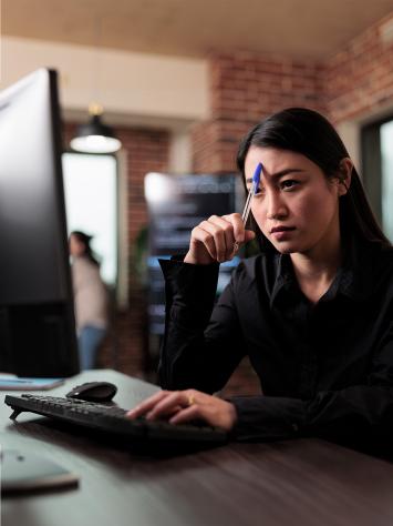 Vrouw kijkt geconcentreerd naar computerscherm